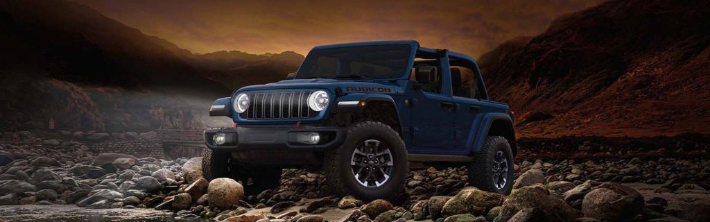 Blue Jeep Gladiator parked on rocky terrain at sunset.